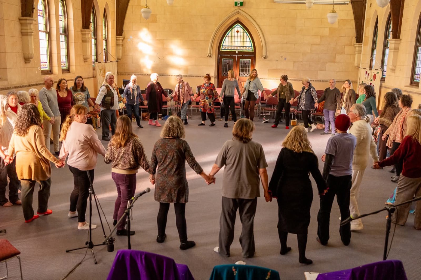 A circle of people holding hands at one of Mello's embodied gatherings